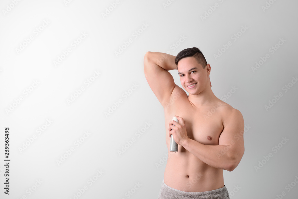 Fototapeta premium Young man with deodorant on light background