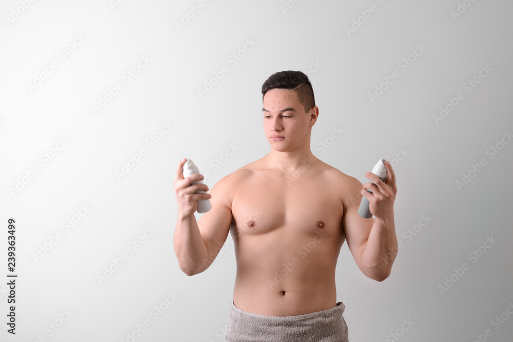 Young man with deodorants on light background Young man with deodorants on light background