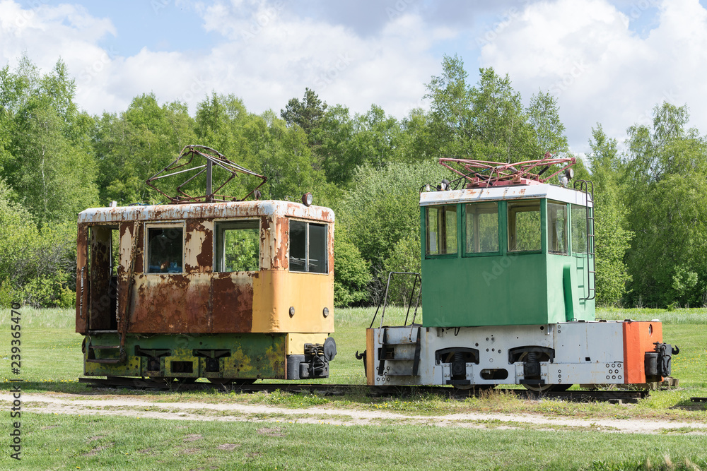 Fototapeta premium Old train and locomotive. Railroad tracks stretches and green grass and trees. Railway road environment background.