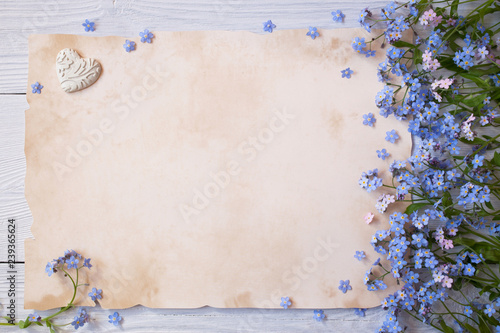 Forget-me-not flowers and greeting paper, letter on wooden background