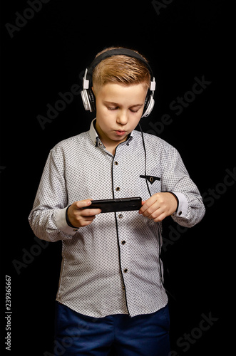 the boy listens to music with headphones and holding a mobile phone.