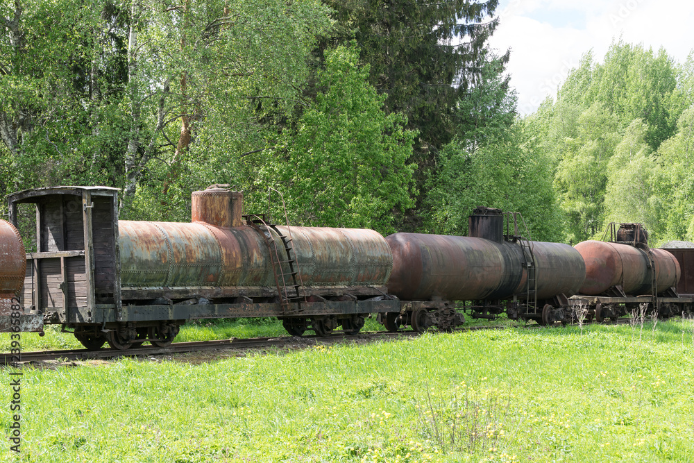 Old train and locomotive. Railroad tracks stretches and green grass and trees. Railway road environment background. Old train and locomotive. Railroad tracks stretches and green grass and trees. Railway road environment background.