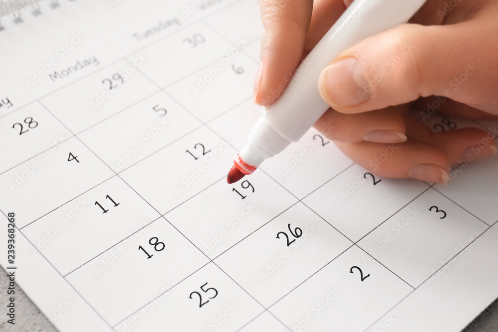 Female hand encircling date in calendar, closeup Female hand encircling date in calendar, closeup
