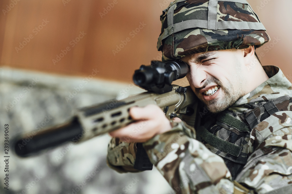 A military soldier targets and holds a large rifle in the building