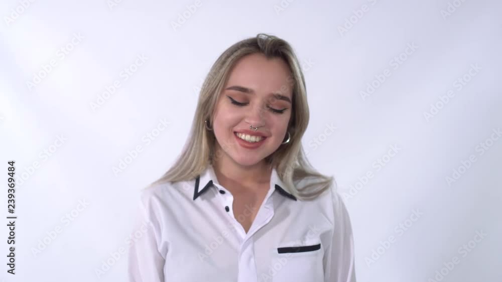 Portrait of a young woman with piercing in the nose in a white shirt smiling at the camera close-up. Portrait of a young woman with piercing in the nose in a white shirt smiling at the camera close-up.