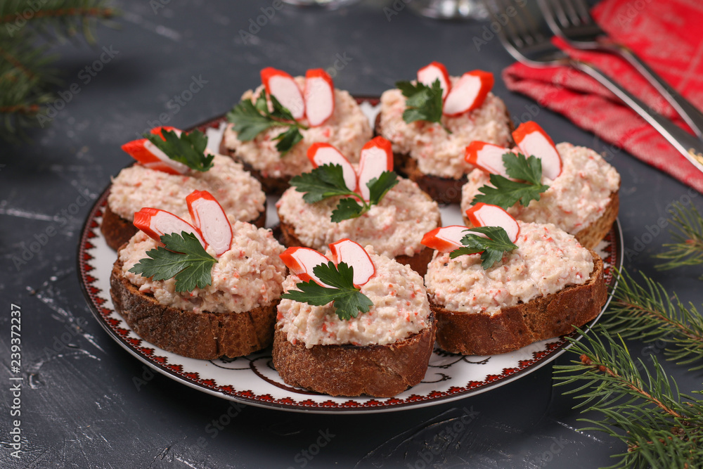 Canapes with cream cheese, crab sticks and beans on the dark background