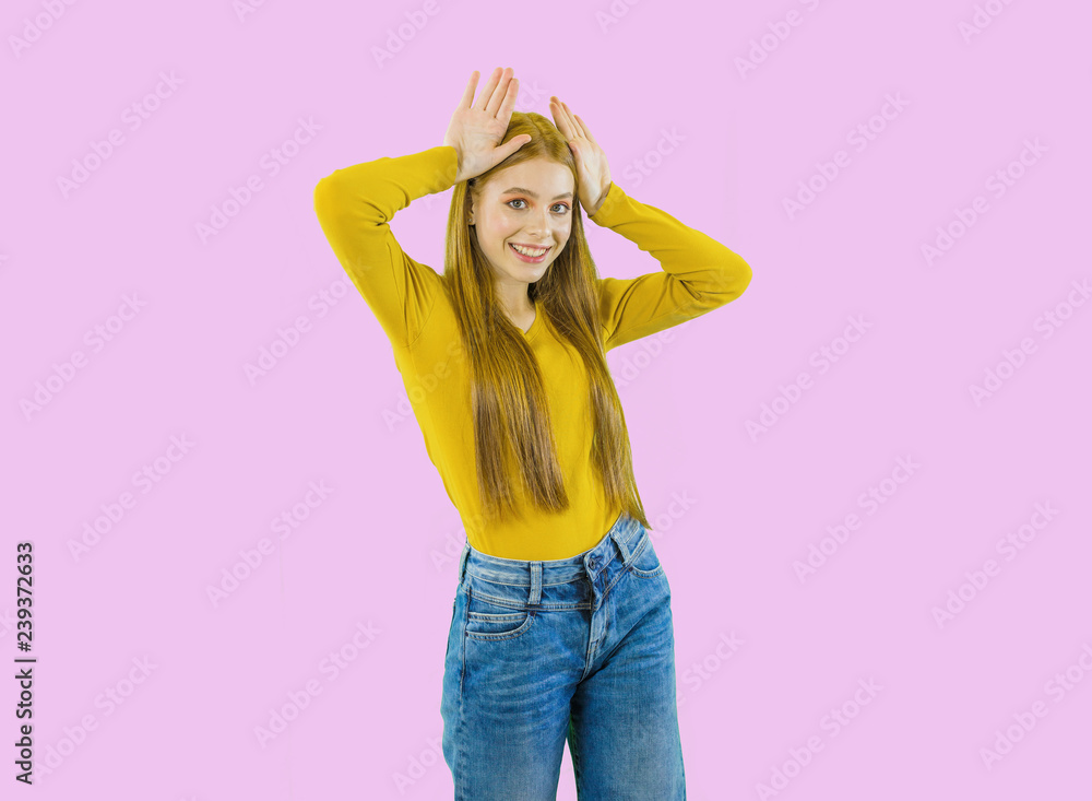 Portrait of a young beautiful red-haired woman playfully smiles and imitates ears with her hands on her head, an idea, shooting on an isolated background Portrait of a young beautiful red-haired woman playfully smiles and imitates ears with her hands on her head, an idea, shooting on an isolated background