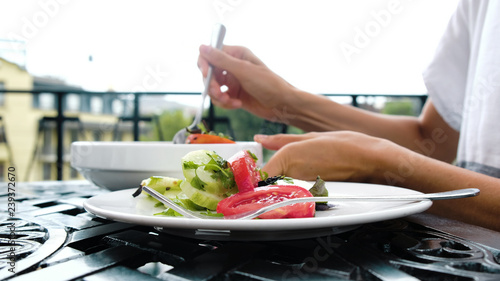 Woman puts a vegetable salad of cucumbers and tomatoes in a plate