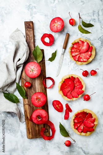 Baking apples pies over white marble table, top view. Cooking mini tarts with fresh red apples Baya Marisa. photo