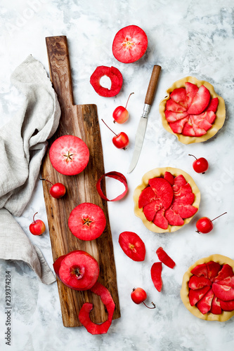 Baking apples pies over white marble table, top view. Cooking mini tarts with fresh red apples Baya Marisa. photo