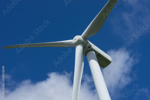 Ecology concept: Blue sky, white clouds and wind turbine. Wind generator for electricity, alternative energy source. Windmill for electric power production.