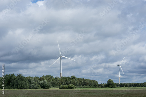 Ecology concept: Blue sky, white clouds, wind turbine and crop field. Wind generator for electricity, alternative energy source. Windmill for electric power production.