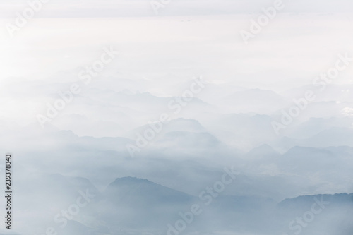 Misty mountain ridges in alps with clouds, aerial view