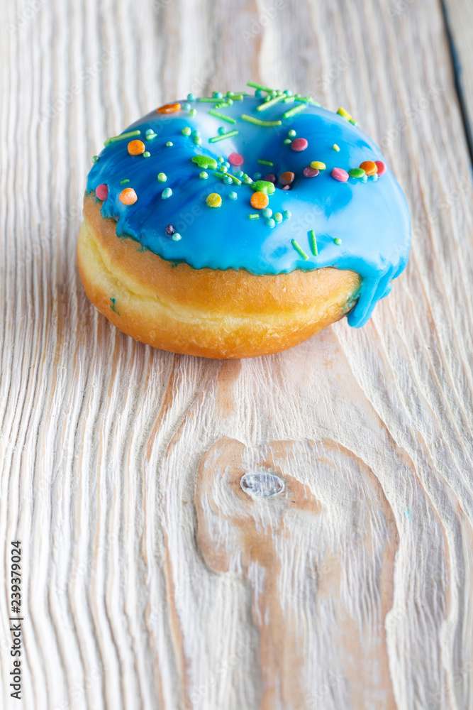 Fresh donut poured with icing and decorations, on a white wooden table Fresh donut poured with icing and decorations, on a white wooden table
