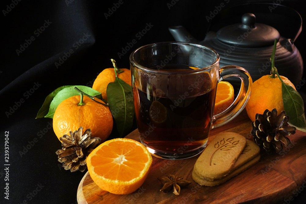 Autumn tea. A cup of black tea, a spoon, autumn leaves, tangerines. Ginger cookies. Black background Autumn tea. A cup of black tea, a spoon, autumn leaves, tangerines. Ginger cookies. Black background
