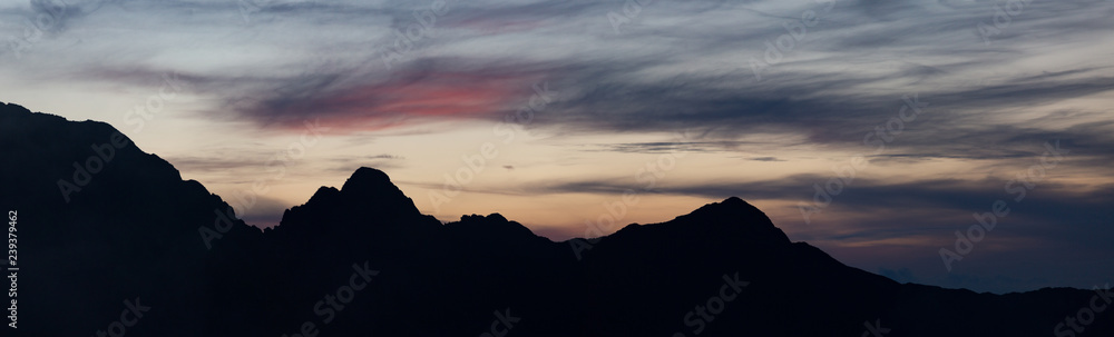High mountain peaks in Romania covered in coloured clouds at sunset.