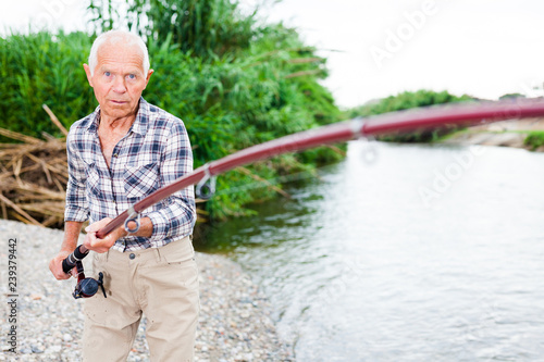 Aged fisherman pulling out catch