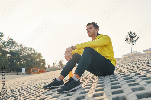 Athletic Man With Fit Body In Yellow Sportswear Resting on Gray
