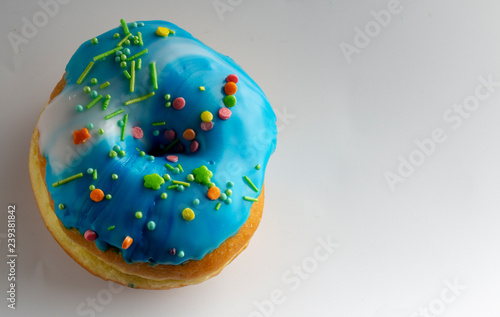 Fresh donut topped with glaze and decorated with colorful decorations on a white background