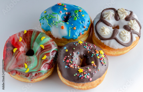 Fresh colorful donuts topped with glaze and decorated with colorful decorations on a white background