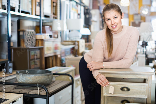 Woman buyer standing in furniture shopping room near chest of drawers