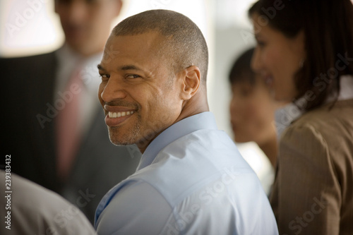 Portrait of a smiling mid-adult businessman looking over his shoulder while standing with his colleagues. photo