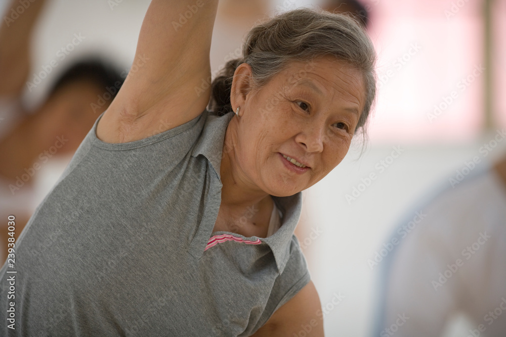 Senior adult woman doing yoga poses with a group of women in a class. Senior adult woman doing yoga poses with a group of women in a class.