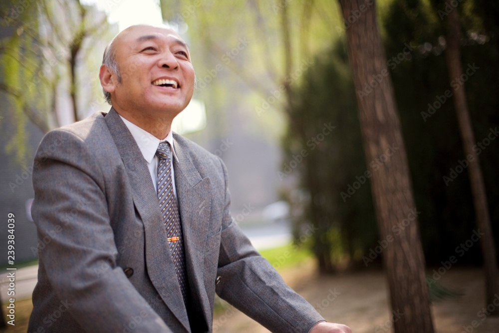 Senior adult businessman riding a bicycle in a park. Senior adult businessman riding a bicycle in a park.