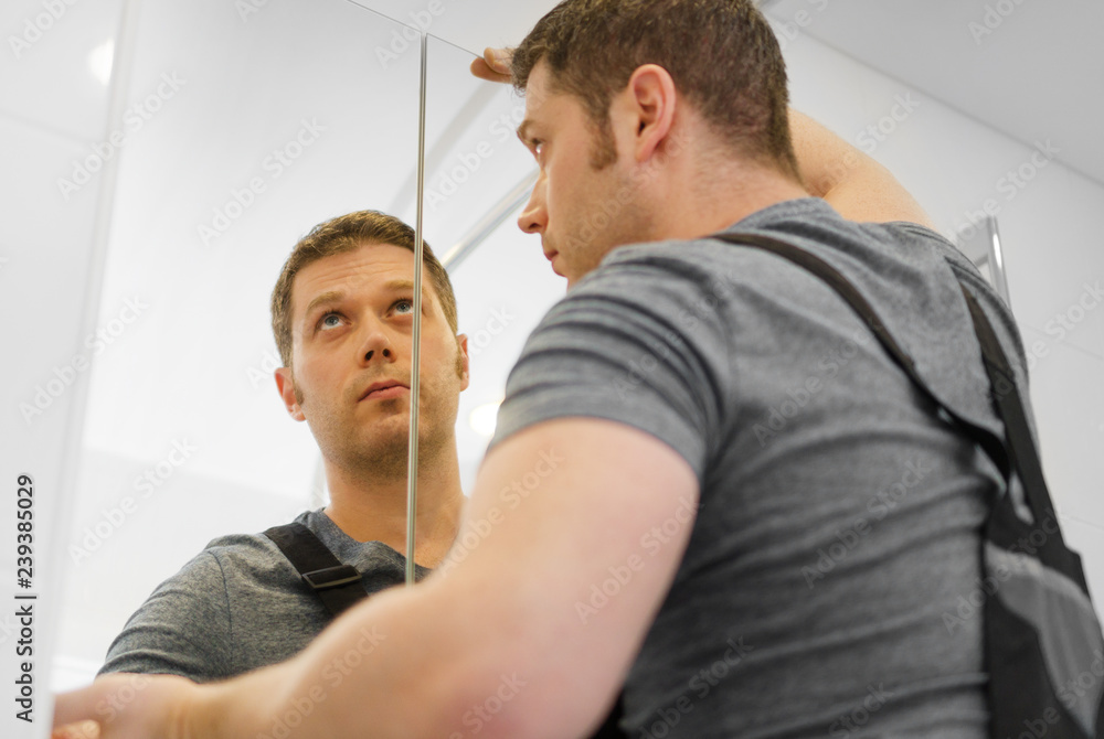 Handyman installing glass cabinet in bathroom. Handyman installing glass cabinet in bathroom.