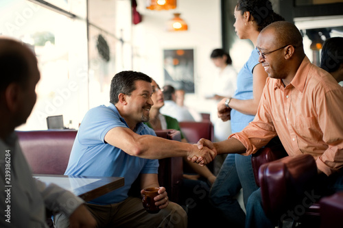 Smiling friends meeting for coffee at a local diner.