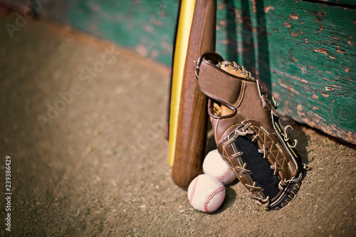 Leather baseball mitt next to baseball bats and balls. photo