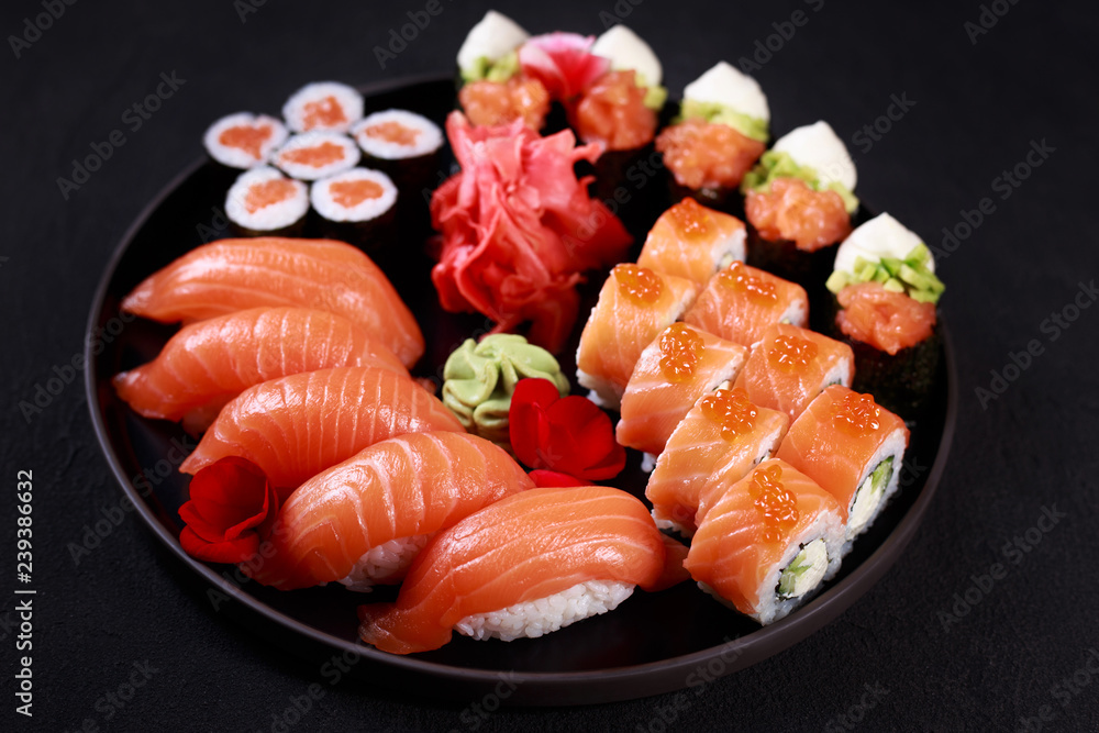 food art, traditional japanese seafood, restaurant menu photo. great colorful set of fresh sushi rolls with salmon, gunkan, nigiri and maki served in black porcelain plate