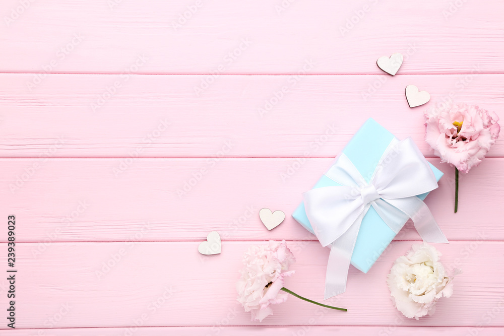 Gift box with eustoma flowers on pink wooden table