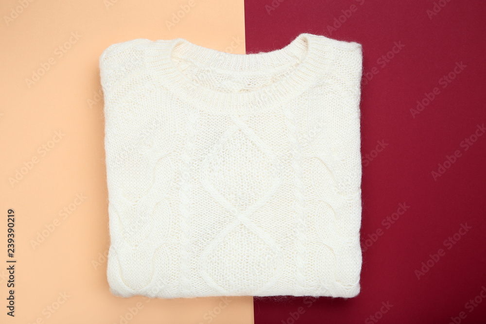 Folded white sweater on colorful background
