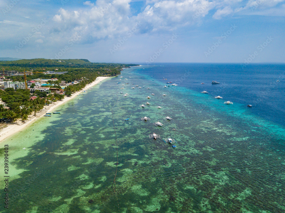 Aerial drone view of Alona beach at Panglao island. Beautiful tropical island landscape with traditional boats, sand beach and palm trees. Bohol, Philippines.