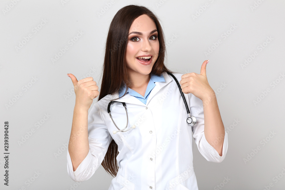 Portrait of young doctor with stethoscope on grey background Portrait of young doctor with stethoscope on grey background