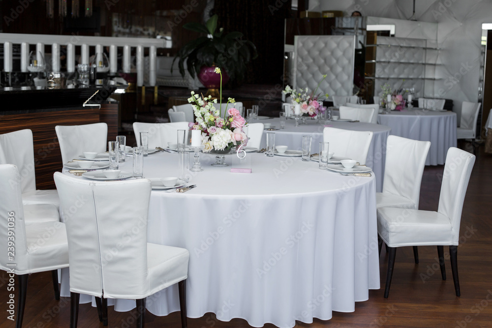 Event white restaurant table served and decorated with delicate fresh flowers Event white restaurant table served and decorated with delicate fresh flowers