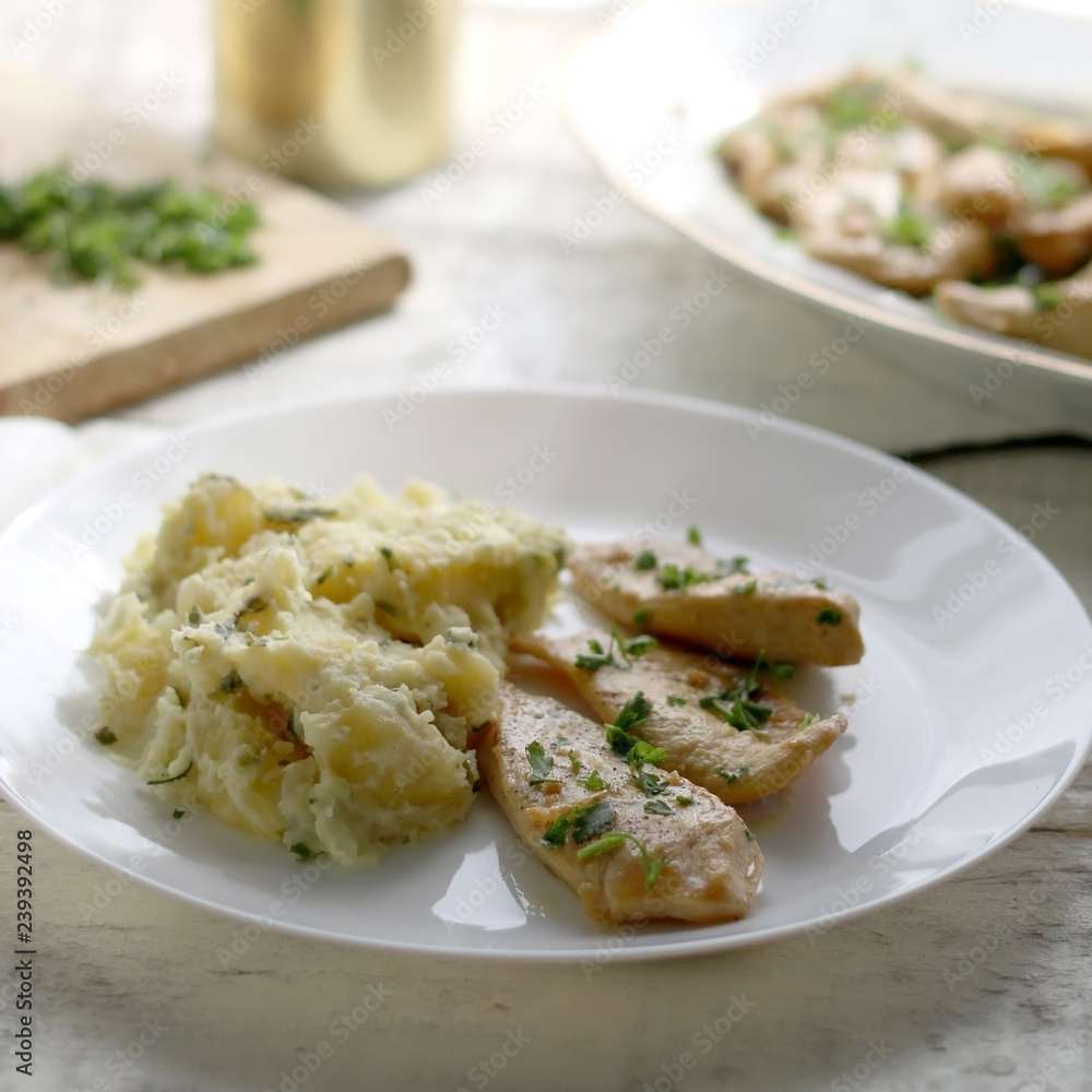 Grilled chicken with fresh parsley and mashed potatoes on a rustic white table. Selective focus. Grilled chicken with fresh parsley and mashed potatoes on a rustic white table. Selective focus.
