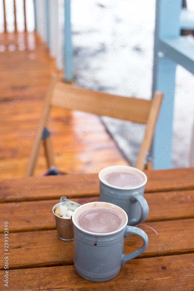 Φωτογραφία Two cups of cocoa and sugar bucket on a wooden table on the outdoor winter terrace