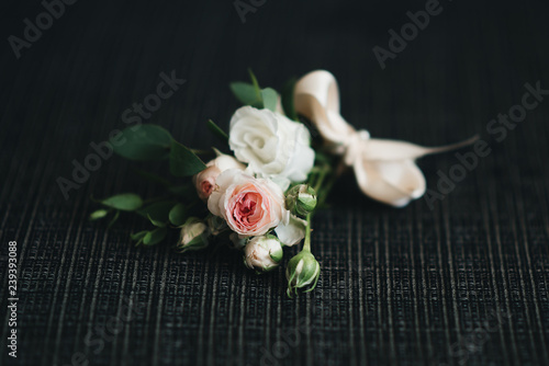 Details of preparing the groom for the wedding, boutonniere on a dark background, selective focus © ksyusha_yanovich