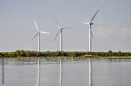 Three modern wind turbines reflecting in lake Grevelingen in the Netherlands on a sunny day photo