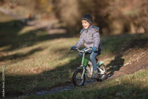 Six years old boy rides bicycle from the hill in the park.