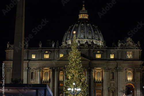 Rome, Italy 12 - 08 - 2018 : St. Peter square, the nativity scene realized with the sand of Jesolo, and the Christmas tree decorated with gold-colored lights. In the background the cathedral. photo