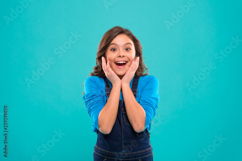 Sincere excitement. Kid girl long healthy shiny hair wear casual clothes. Little girl excited happy face. Kid happy cute face feels excited blue background. Exciting moments. Excitement emotion