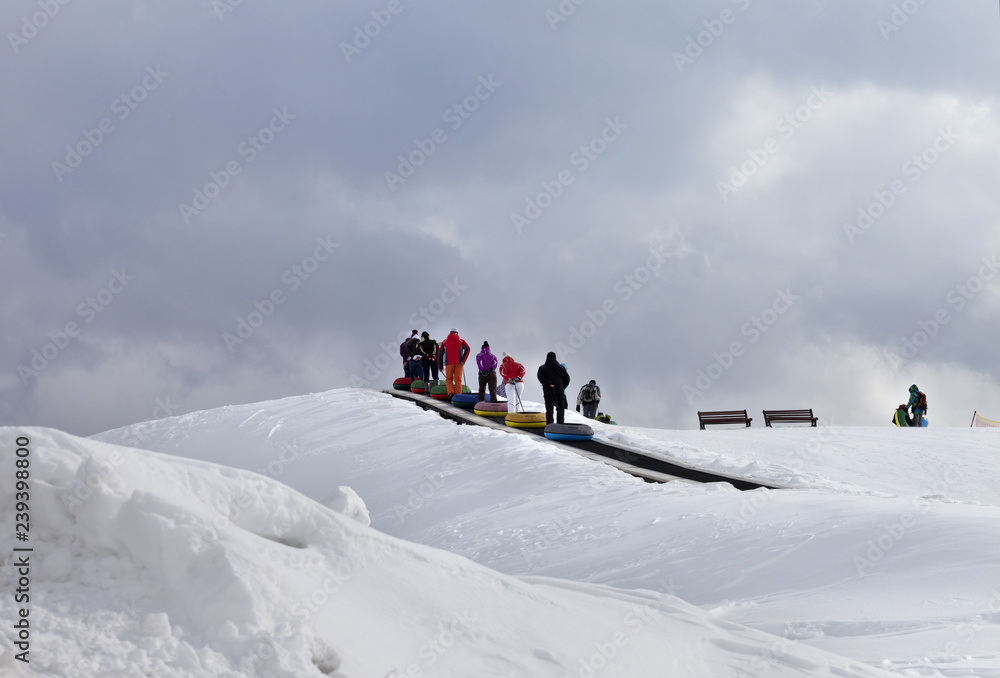 People move up on moving carpets with snow tube at ski resort