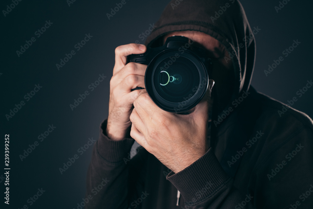 Hooded photographer behindDSLR camera Hooded photographer behindDSLR camera
