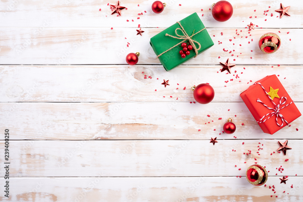 Christmas background concept. Top view of Christmas green and red gift box with spruce branches, pine cones, red berries and bell on white wooden background. Christmas background concept. Top view of Christmas green and red gift box with spruce branches, pine cones, red berries and bell on white wooden background.
