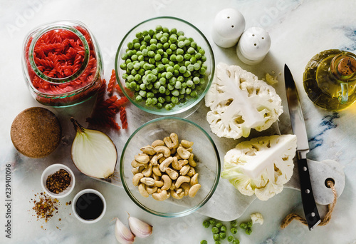 fresh ingredients for a gluten-free red lentil pasta with cauliflower and green peas with olive oil and spices on the marble table . healthy vegan cuisine