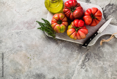 brandywine tomato on a cutting board. cooking summer salad with fresh olive oil, thyme. on a stone table