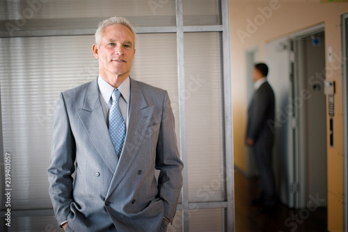 Portrait of a mature businessman standing with hands in his pockets in an office. photo